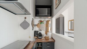 Una cocina compacta con microondas, cafetera y un mueble pequeño.
