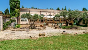Un edificio con jardín, una pérgola y un árbol alto.