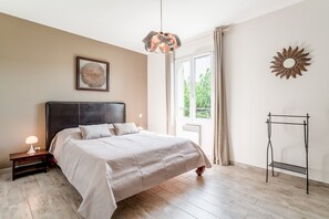 A bedroom with a bed, bedside table, lamp, window, and decorative wall art. - Holiday Home 'Villa Les Joncs D'Octobre' with Private Pool, Wi-Fi and Air Conditioning (Jonquerettes)