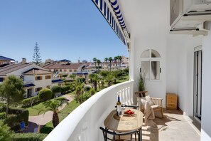 A balcony with a table, chairs, and a view of the surrounding buildings and greenery. - Apartment with Sea View, 300m from the Beach (La Mata)