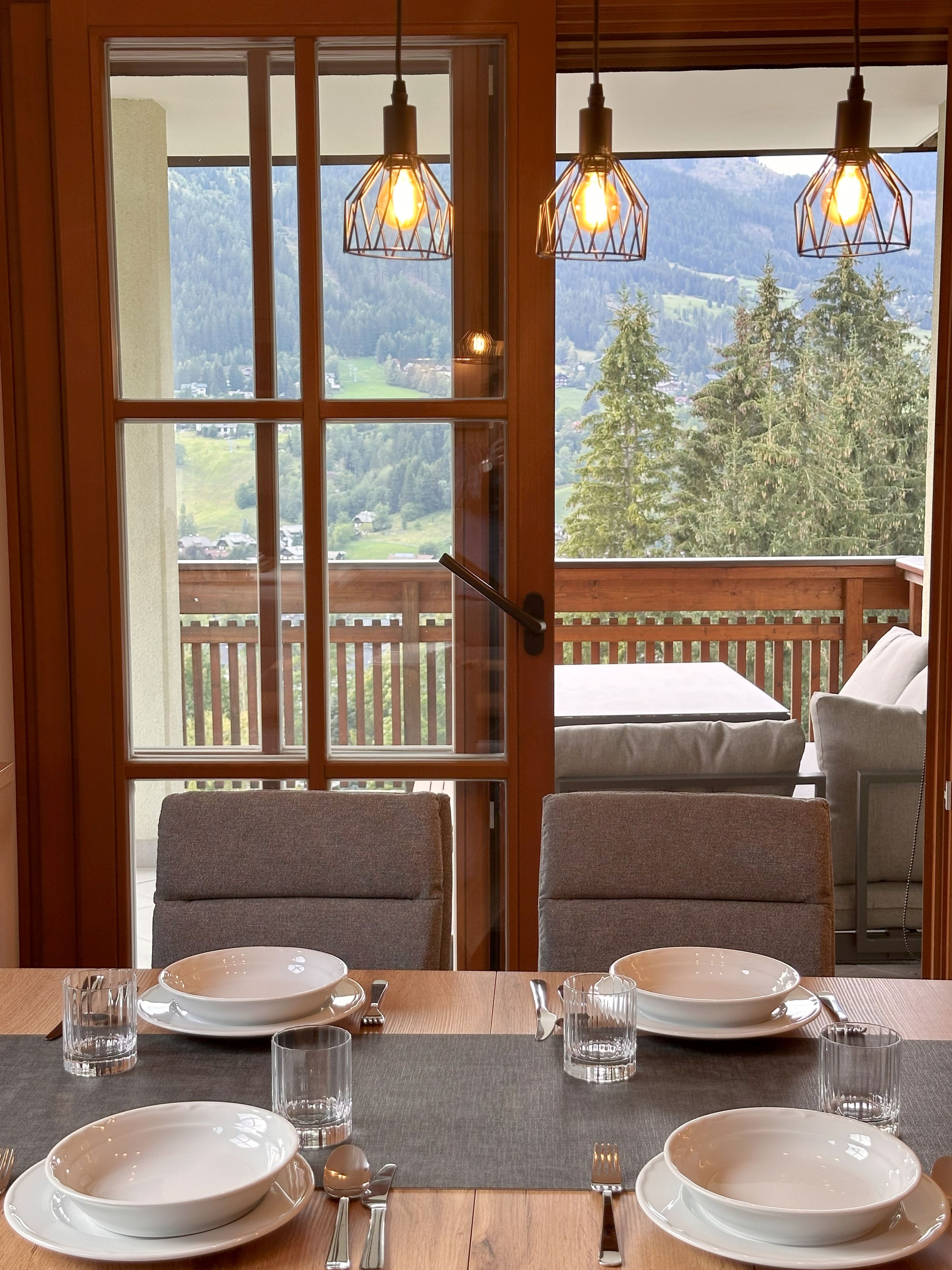 A dining area with a table set for four, overlooking a mountainous landscape.