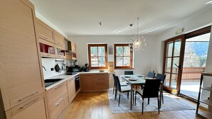 Una cucina moderna con mobili in legno, un tavolo da pranzo con sedie e un'ampia finestra vista all'esterno.
