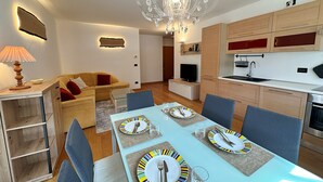 Un appartamento moderno con sala da pranzo, cucina, soggiorno e un lampadario.
