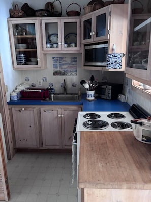 Une cuisine avec des meubles de rangement en bois, une cuisinière, un four à micro-ondes et un évier.