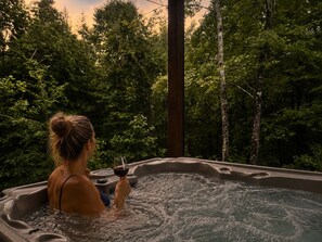 Una persona en un jacuzzi rodeado de un bosque frondoso.