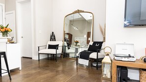 A modern living room with a large mirror, a wooden coffee table, a white sofa, a black armchair, and a small side table with a lamp. - New 2-bedroom corporate loft in charming Atlanta, right by the airport. (Atlanta)