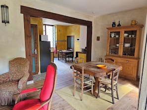 A dining area with a wooden table and chairs, a red chair, a cabinet with dishes, and a patterned sofa. - The Seigneury (Saint-Martial)