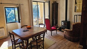 Ein Zimmer mit einem Holztisch, Stühlen, einem roten Sessel, einem Kamin und Blick durch ein Fenster.