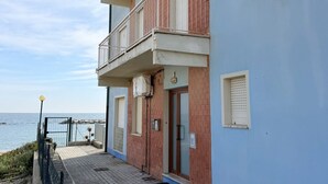 Un bâtiment situé sur la côte, doté d’un balcon, d’une porte et offrant une vue sur la mer.