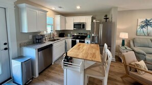 Una cocina moderna con armarios blancos, una mesa de comedor de madera y un microondas empotrado.