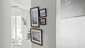 Ein Korridor mit einer weißen Tür, einem kleinen Tisch mit Büchern und gerahmten Bildern an der Wand.