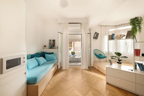 A compact living space with a sofa, a dining area, and a kitchenette. - Estia Premium Apartments - Capri Blue Salonica (Thessaloniki)