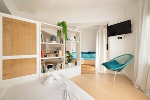 A modern living room with a sofa, a TV, and a bookshelf. - Estia Premium Apartments - Capri Blue Salonica (Thessaloniki)