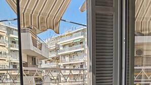 Ein Balkon mit Tisch und Stühlen, einer Obstschale und Blick auf ein mehrstöckiges Gebäude.