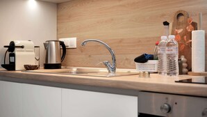 A modern kitchen with a stainless steel sink, a coffee maker, a kettle, and a wooden backsplash. - Estia Premium Apartments - Superior Suite Vackhou 1 #1.2 (Thessaloniki)