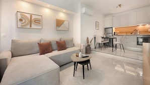 A modern living room with a sectional sofa, a coffee table, and a dining area with chairs. - Estia Premium Apartments - Superior Suite Vackhou 1 #1.2 (Thessaloniki)