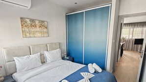 Une chambre d’hôtel moderne avec un grand lit, un mur d’accent bleu, un luminaire au plafond et un tableau accroché au mur.