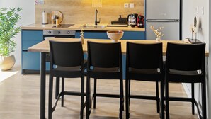 Eine moderne Küche mit blauen Schränken, einer Holz Arbeitsplatte und einem Essbereich mit vier Stühlen.