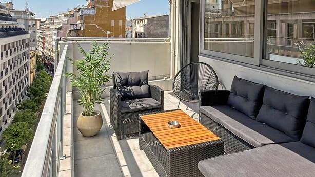 Eine Dachterrasse mit Gartenmöbeln, einem Blumentopf und Blick auf die Skyline.