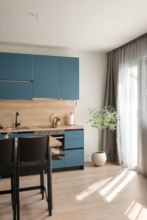 Eine moderne Küche mit blauen Schränken, einer Holz Arbeitsplatte, einem Spülbecken und einem Essbereich mit Stühlen.