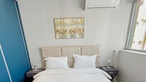 Ein Hotelzimmer mit Bett, einem Gemälde, einer Klimaanlage und einem Fenster.