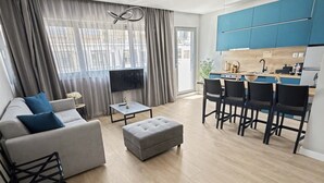 Ein modernes Wohnzimmer mit einer Couch, einem Hocker und einem Essbereich mit Stühlen.