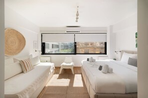 Une chambre moderne avec deux lits, une grande fenêtre et une vue sur les bâtiments environnants.