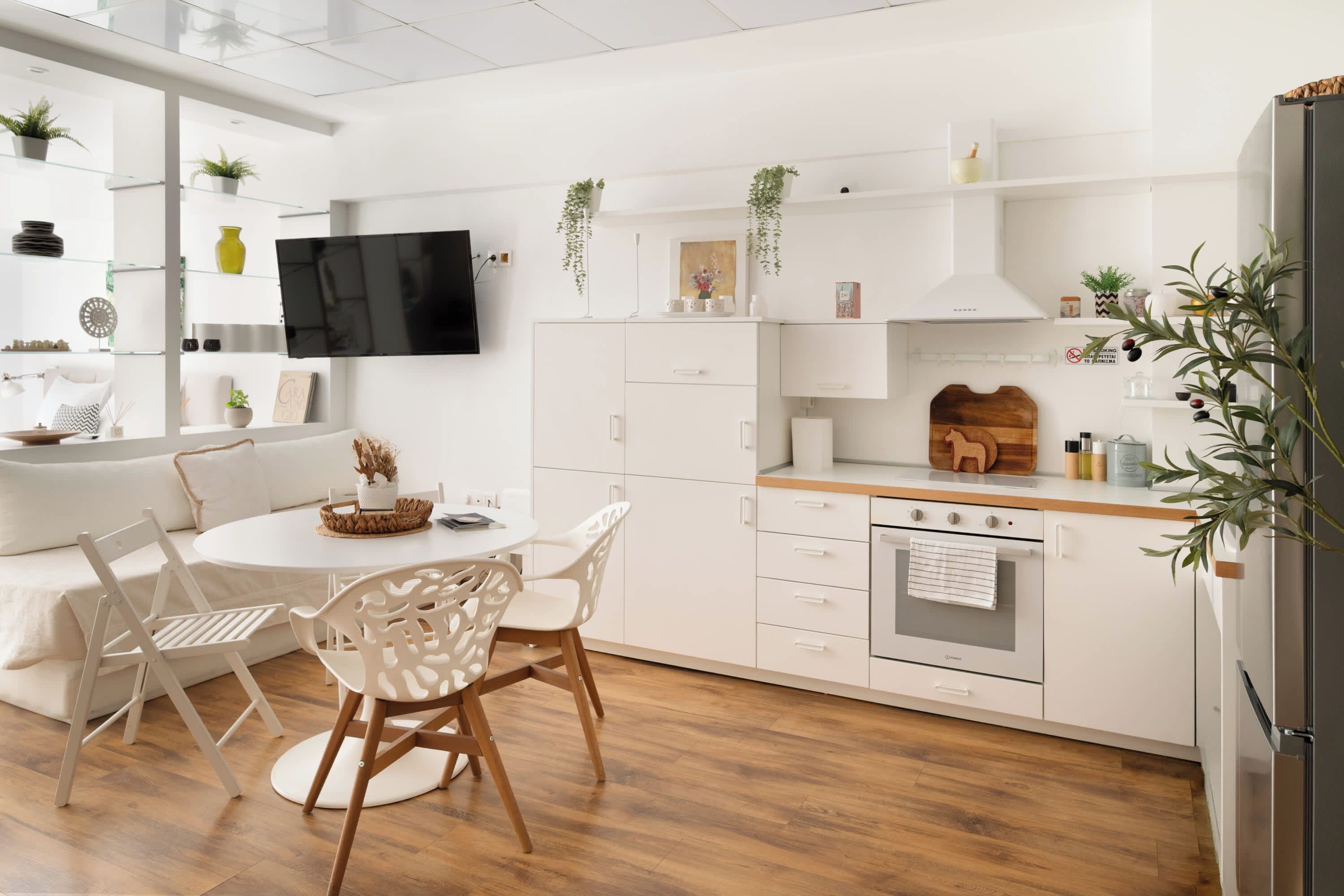 Une cuisine moderne avec des meubles blancs, une table à manger en bois et des chaises.