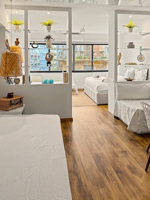 Una camera d'hotel moderna con un letto grande, un divano, un tavolino e vista sulla città attraverso ampie finestre.