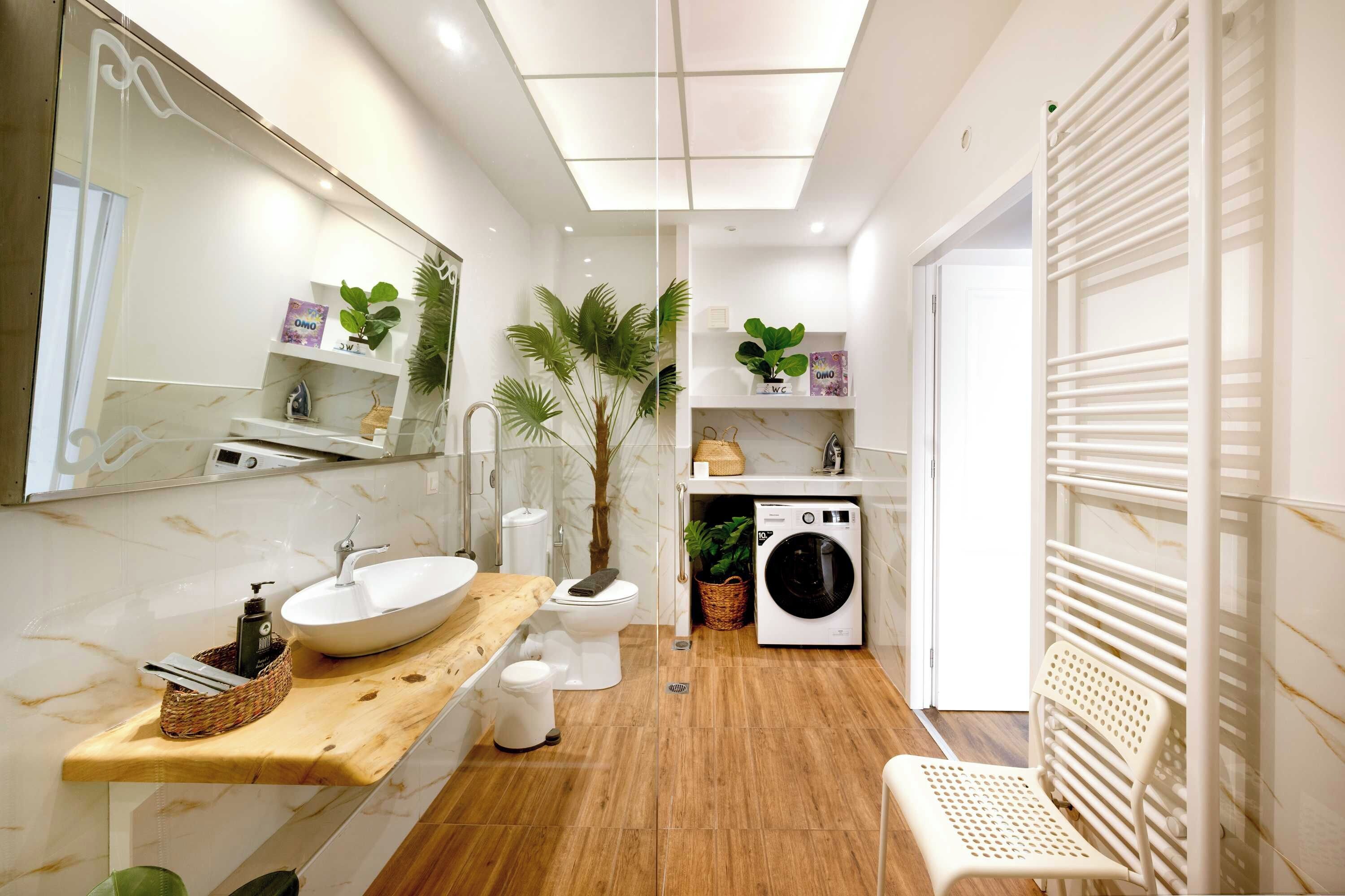 Une salle de bain moderne avec un grand miroir, un meuble-lavabo en bois, un évier, des toilettes, un lave-linge et un espace douche.