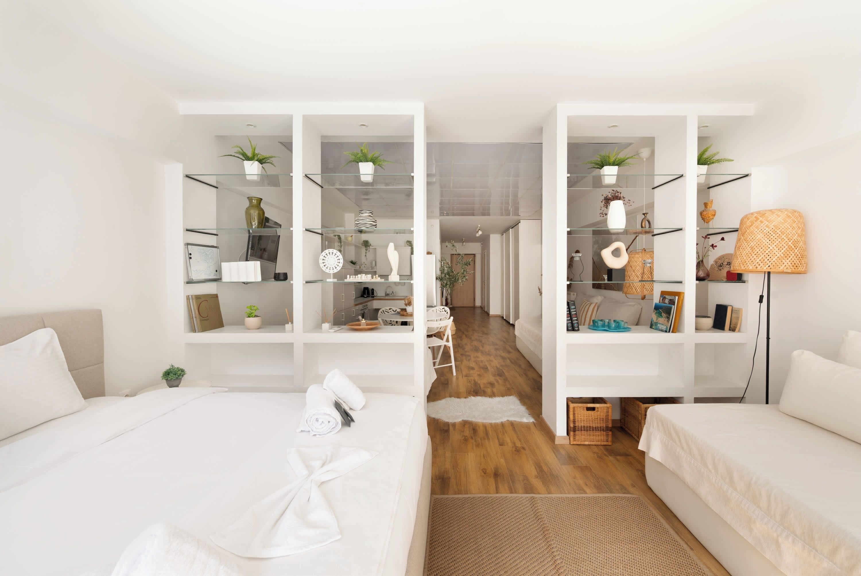 A modern bedroom with a large bed, a desk, and a kitchenette.