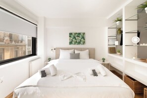 Une chambre moderne avec un grand lit, une vue sur la ville et un décor minimaliste.