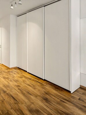 Une pièce avec un plancher en bois, des murs blancs et une porte coulissante.
