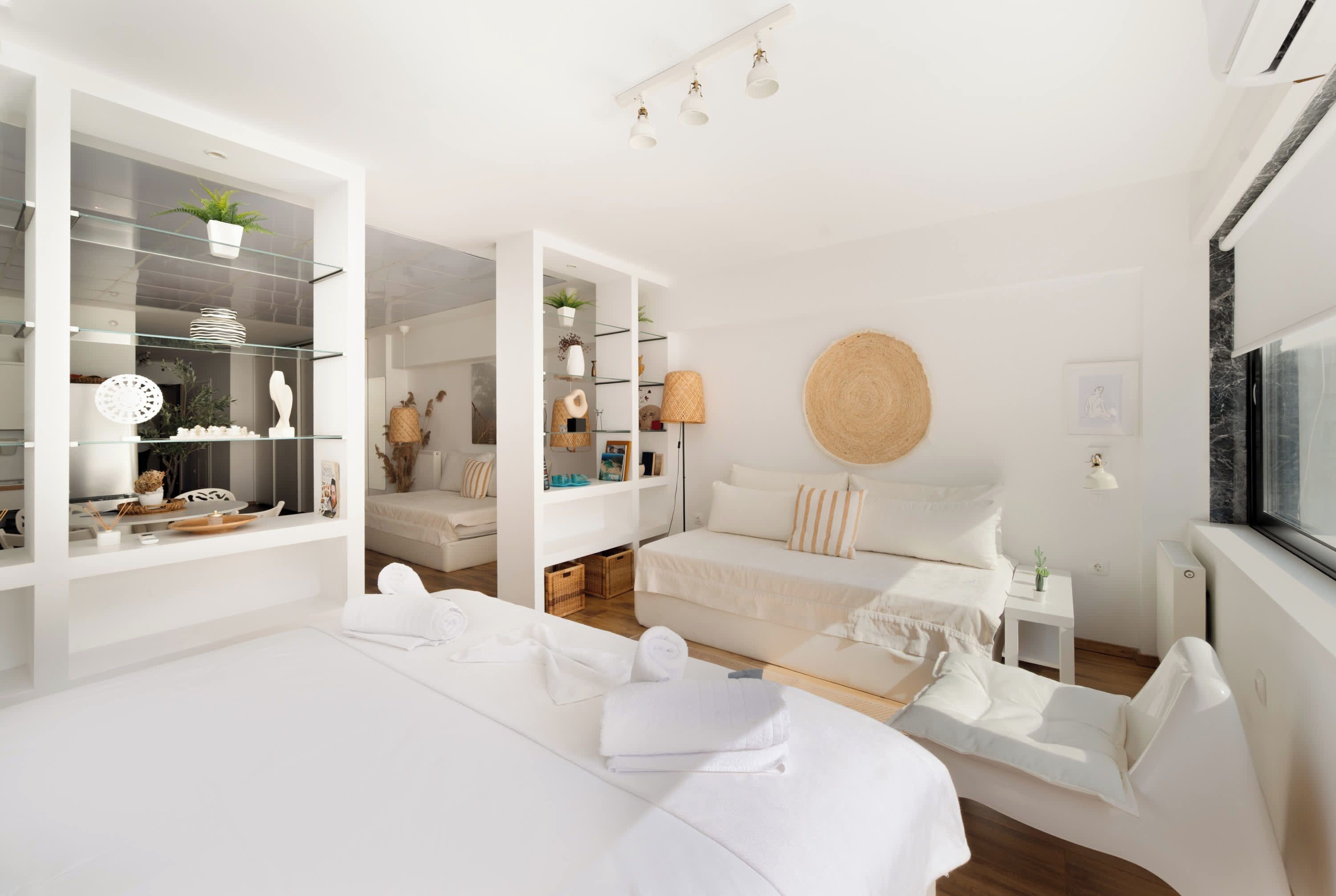 Une chambre à coucher moderne et minimaliste, dotée d’un grand lit, d’un petit canapé et d’un dressing avec des portes en verre.
