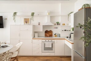 Une cuisine moderne avec des meubles blancs, un four encastré et un réfrigérateur.