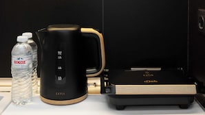 A black electric kettle with a wooden handle, a water bottle, and a black portable charger with a wooden side panel.