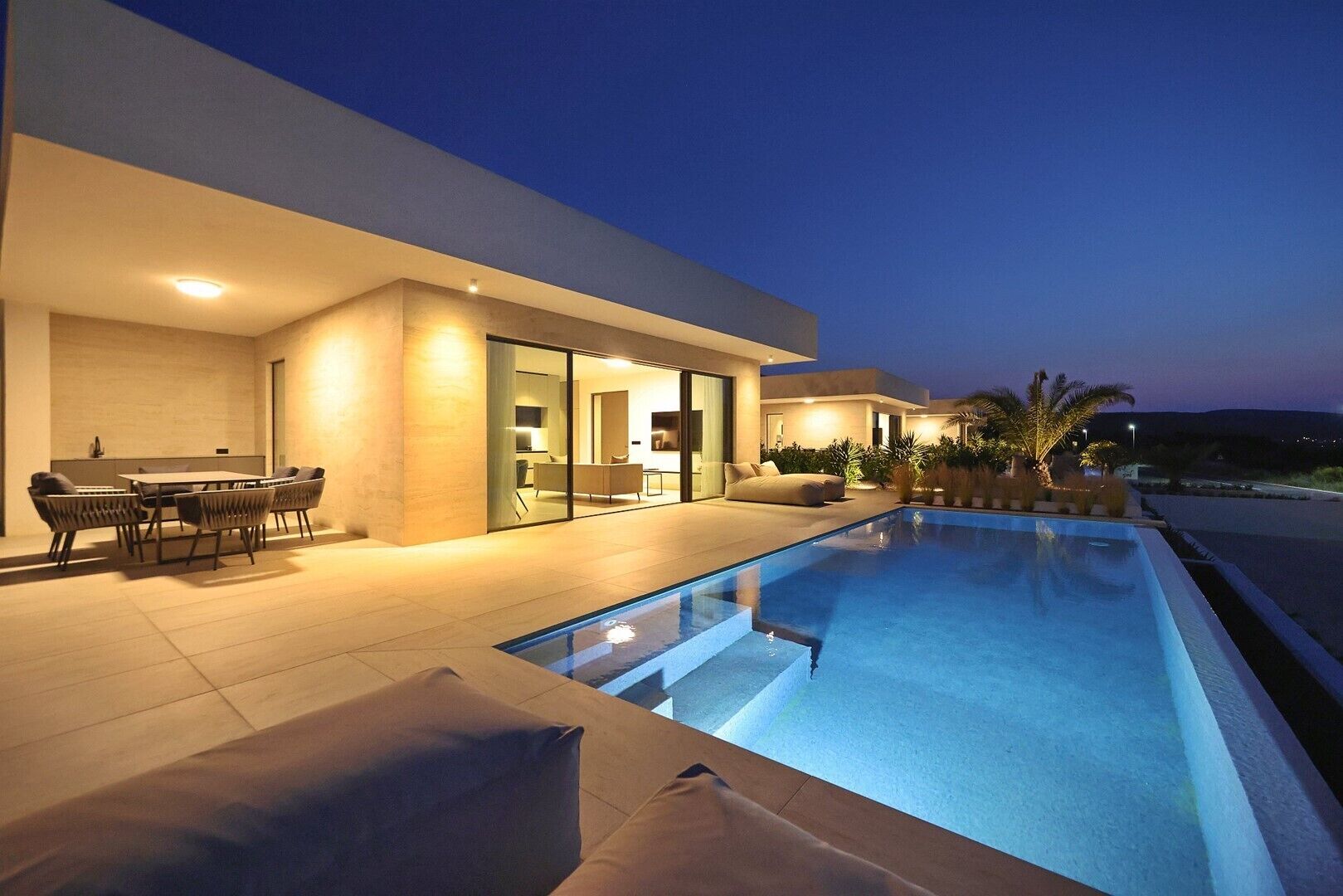 A modern house with a swimming pool, outdoor furniture, and a patio area.