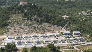 Uma área residencial moderna, com casas isoladas e um edifício grande com telhado vermelho.