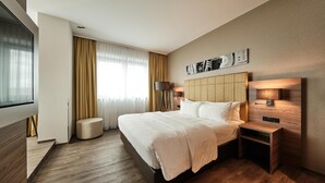 A modern hotel room with a large bed, a bedside table, a lamp, and a wall-mounted artwork. - Radisson Blu Hotel, Bonn (T) (Bonn)