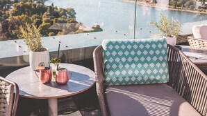 A balcony with a view of a river, a table with drinks, and a cushioned chair. - Radisson Blu Hotel, Bonn (T) (Bonn)
