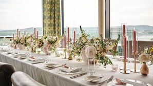A table set for a meal with floral centerpieces, candles, and a view of the outdoors. - Radisson Blu Hotel, Bonn (T) (Bonn)
