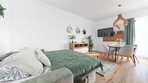 Un dormitorio moderno con cama, mesita de noche y una zona de comedor con sillas y mesa.