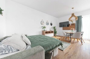 A modern bedroom with a bed, bedside table, and a dining area with chairs and a table. - Kajetanka Residence - with terrace and free parking on weekends (Hlavní město Praha)