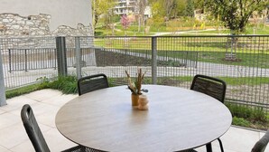 Una mesa redonda con sillas, una planta en maceta y una pared de piedra.