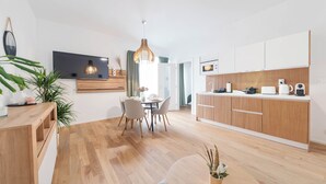 Una cocina moderna con armarios de madera, un comedor con mesa y sillas, y un televisor montado en la pared.