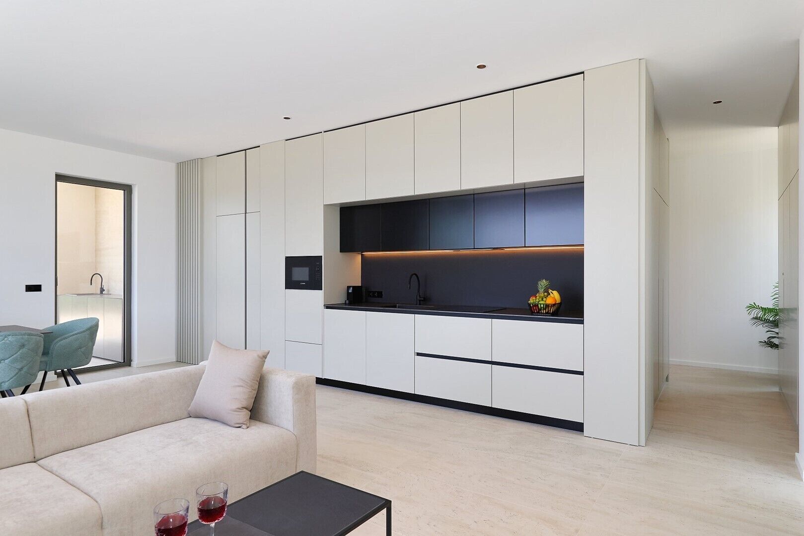 Une cuisine moderne dotée d’appareils électroménagers intégrés, un coin repas avec un canapé et une table, et une salle de bain visible.