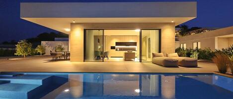 A modern house with a swimming pool, a dining area, and a living room with a sofa.