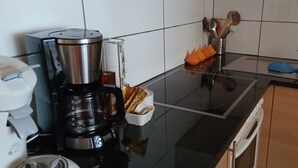 A kitchen with a coffee maker, a container with orange items, and a sink.