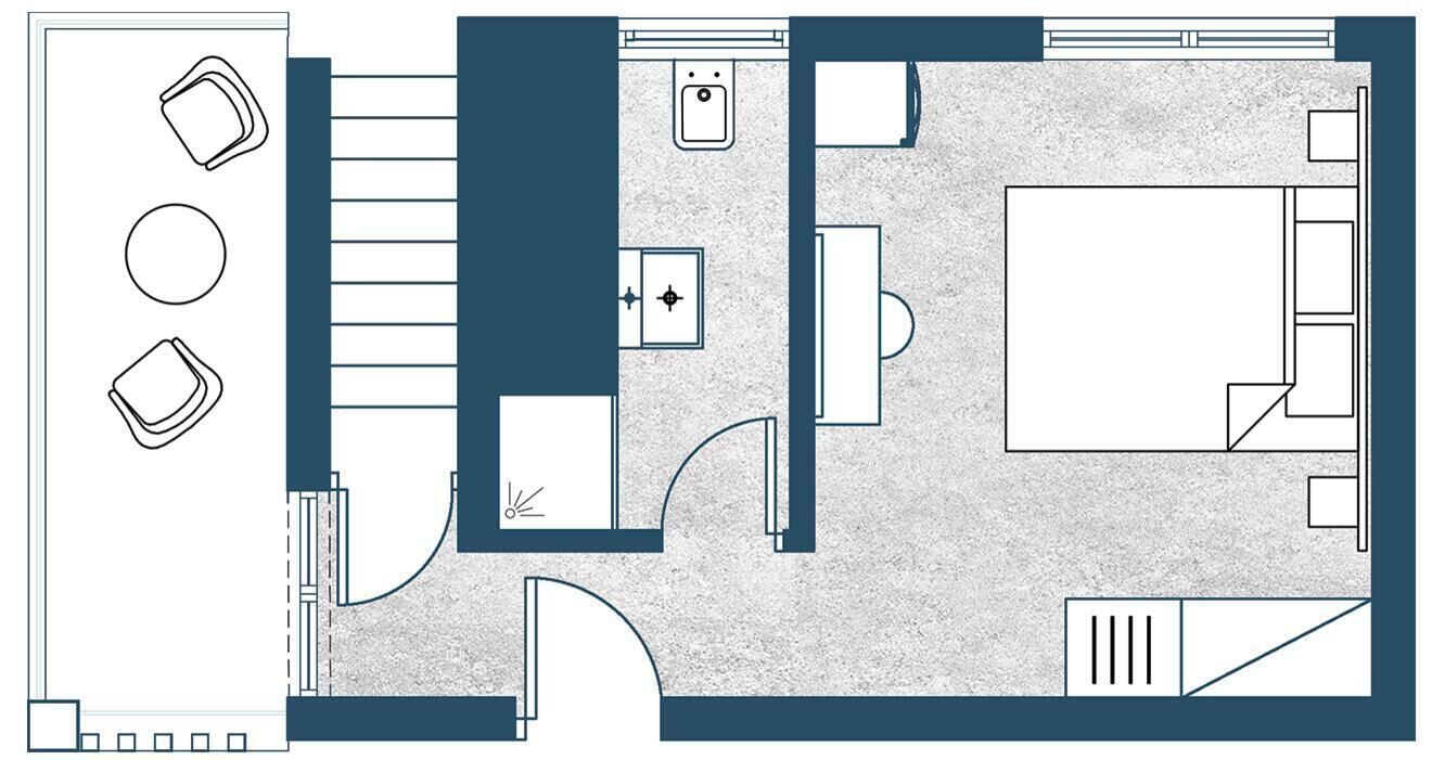 A hotel room layout with a bed, seating area, and a small kitchenette.