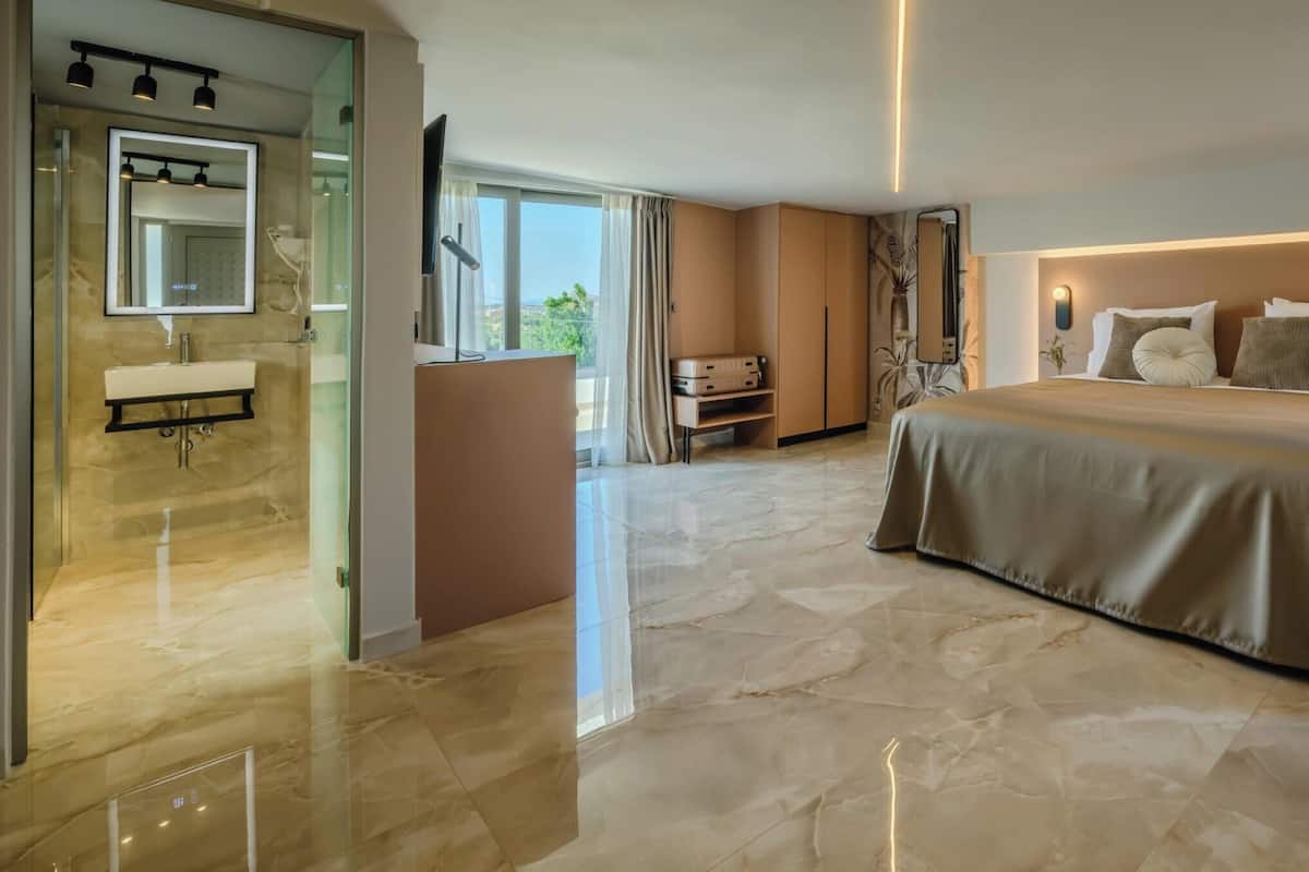 A modern hotel room with a large bed, a bathroom with a vanity, and a view of the outdoors.